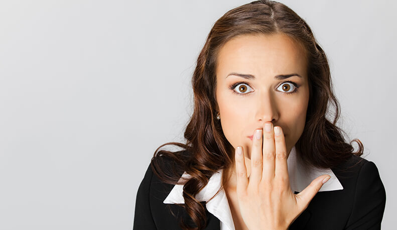 Business woman covering with hands her mouth, over grey
