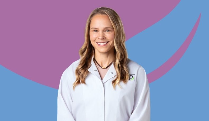 Dr. Audrey Cyr in a white Park Dental clinical jacket posed in front of a purple and blue background
