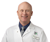 Dr. Steve Bakke, wearing a white coat with a Park Dental logo, smiles at the camera.