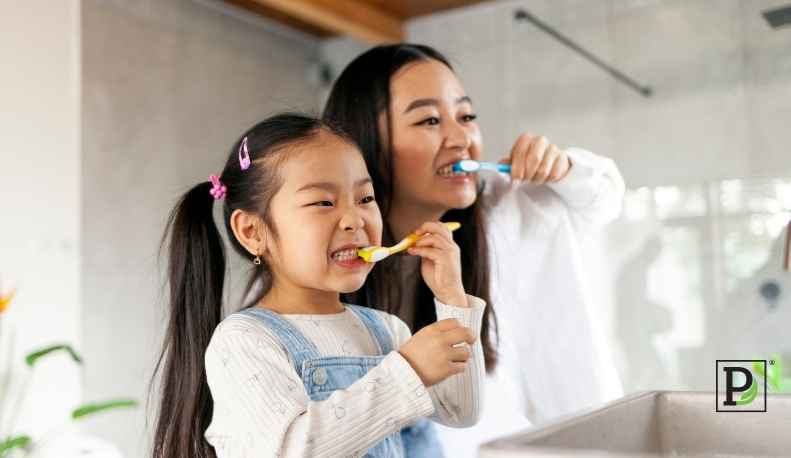 mother and daughter brushing their teeth together.
