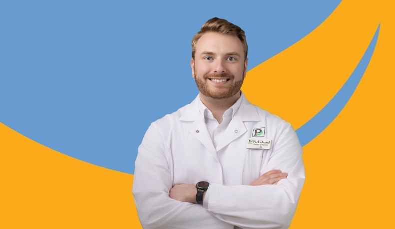 Dr. Gregory Martens posing in a clinical jacket in front of a blue and orange background.