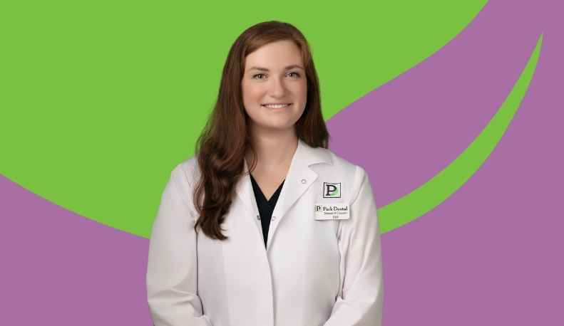 Dr. Shimrit Cassuto posing in a clinical jacket in front of a green and purple background.