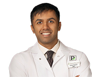 SharmaTushar-050_web Dr. Tushar Sharma smiling in a clinical jacket with the Park Dental logo.