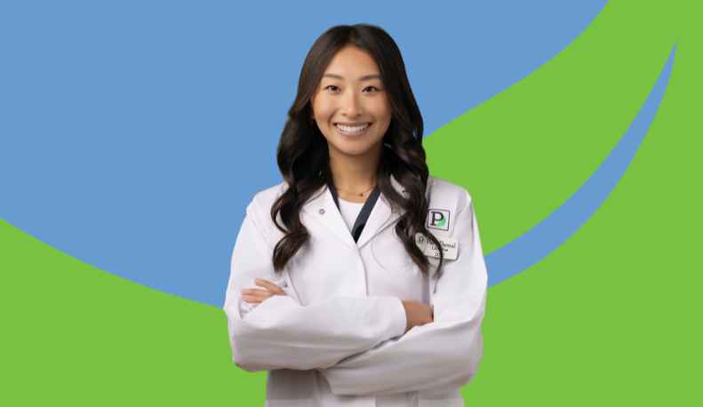 Dr. Lilly Vue posing in a clinical jacket in front of a green and blue leaf background.